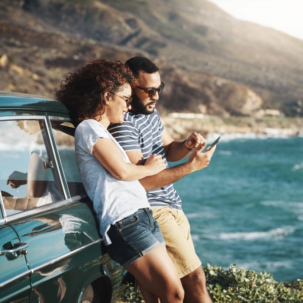 Shot of a young couple using a mobile phone on a road trip